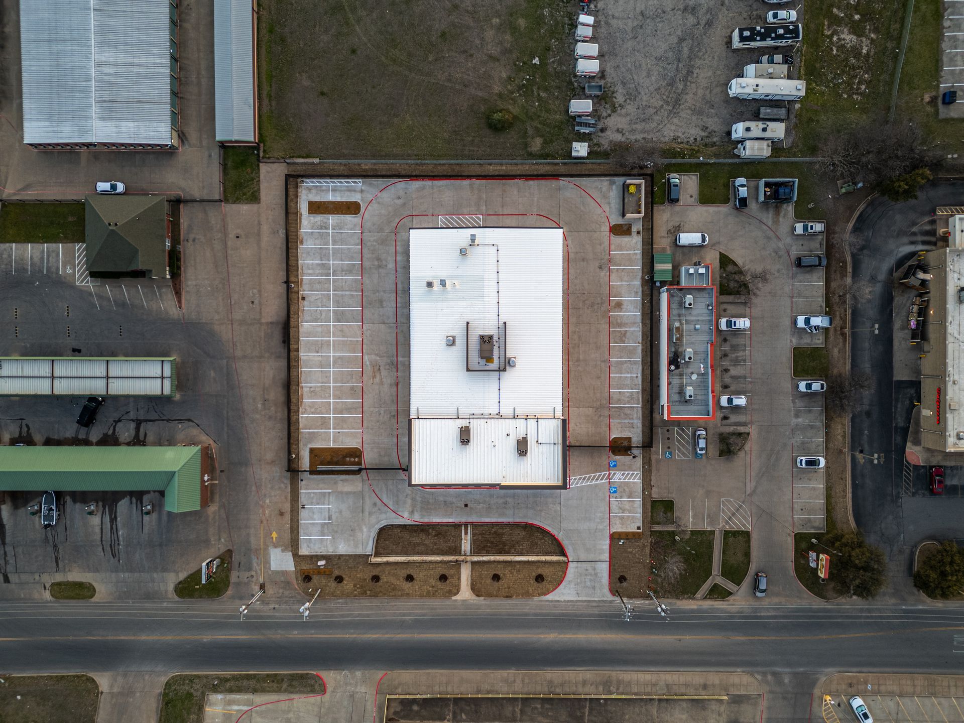 Overhead view of a commercial building and surrounding parking areas in a town.