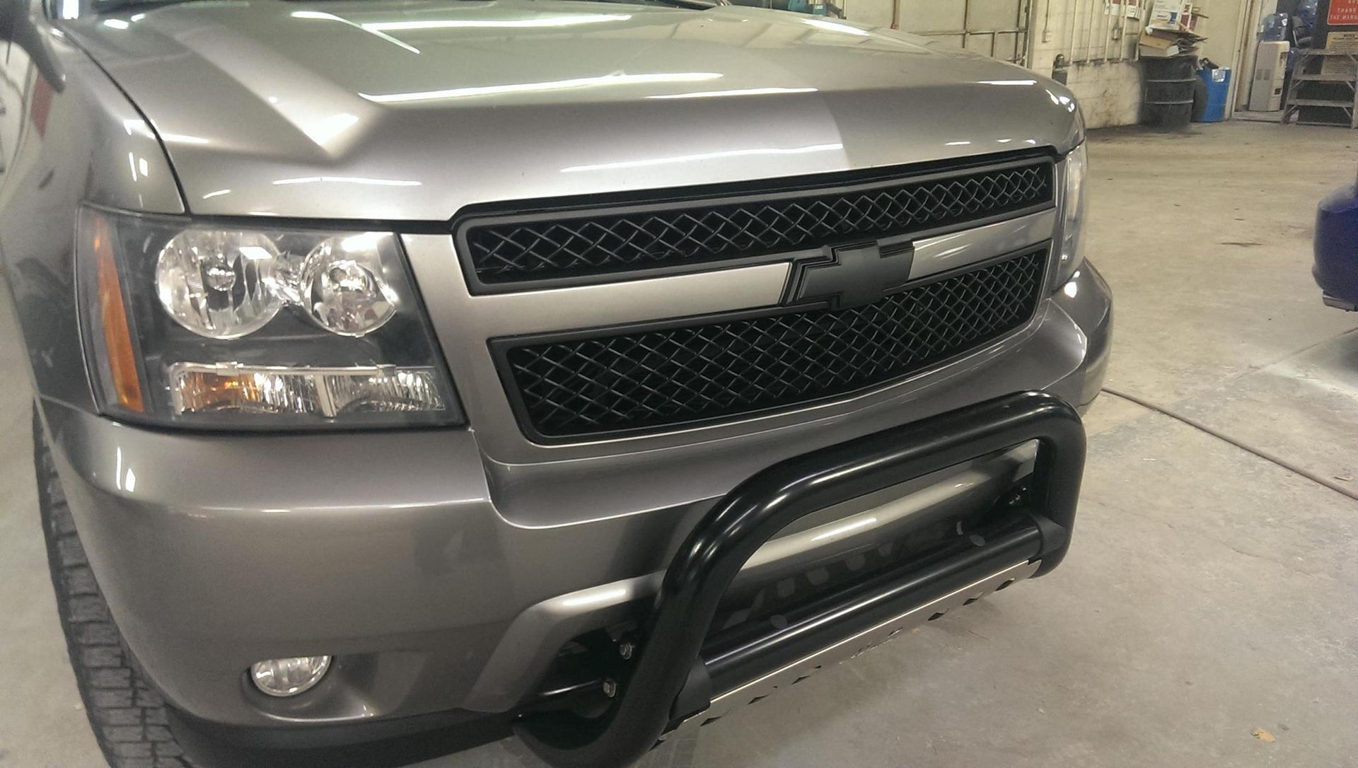 Gray Chevrolet truck with black grille and bull bar in a garage.
