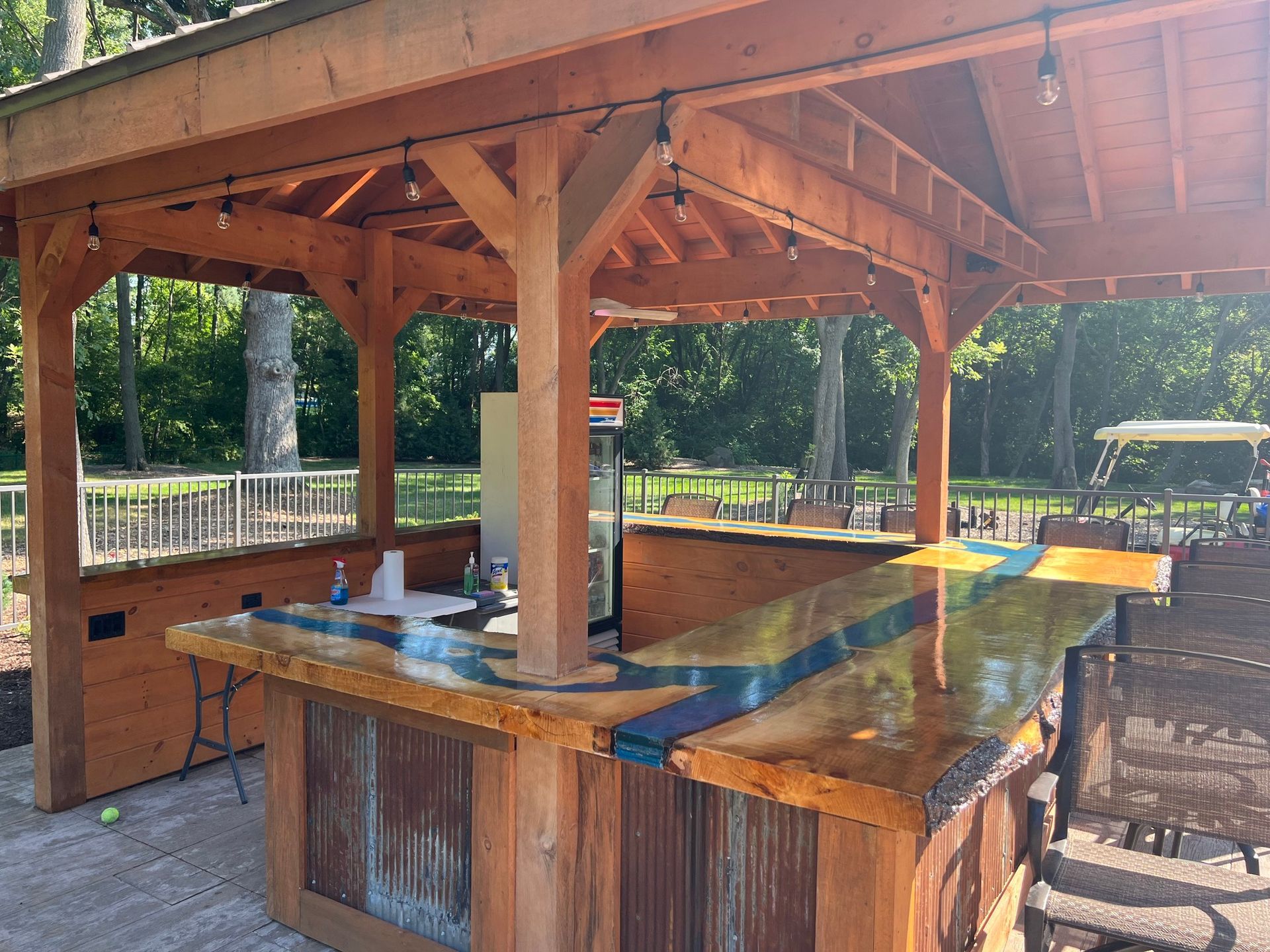 Wooden outdoor pavilion with a large granite-topped bar and high stools under a shingled roof