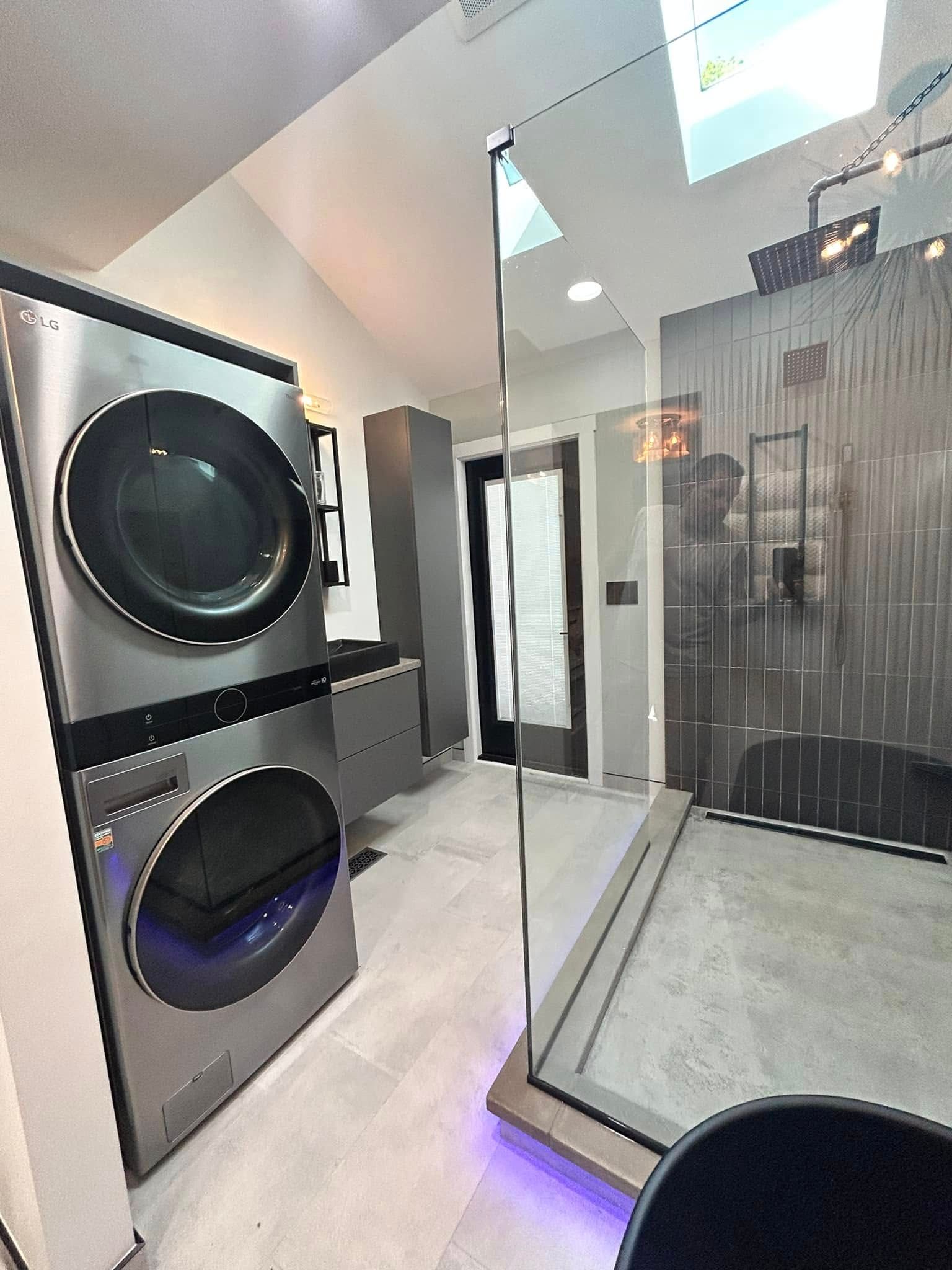 Modern bathroom with glass shower, marble tile, and stacked black speakers on the left.