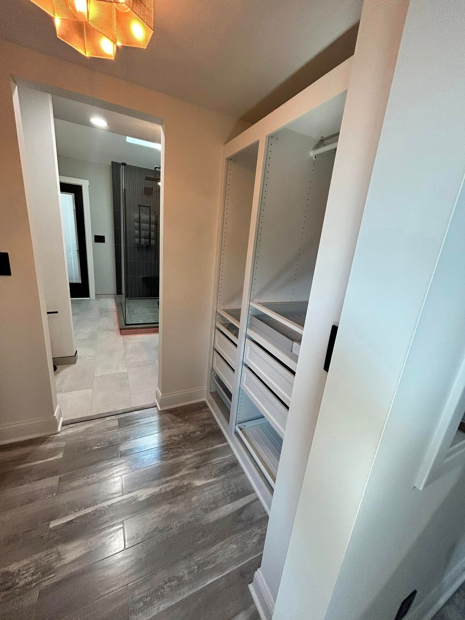 Hallway with gray wood flooring, mirrored closet door, and open built-in shelving.