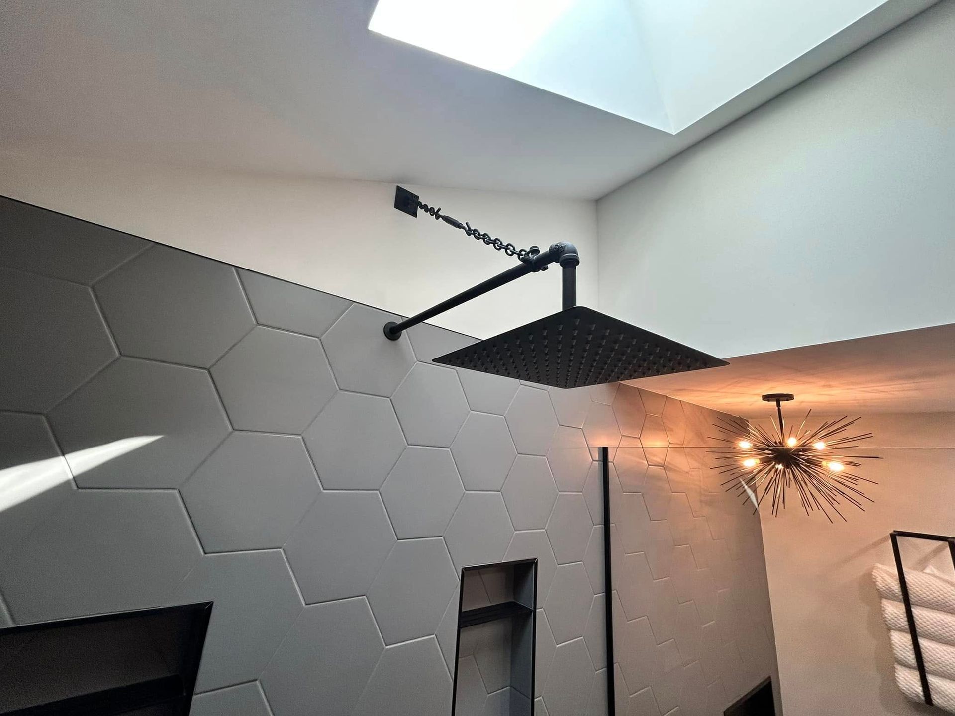Modern room with hexagon wall panels, skylight, and a hanging fireplace with a warm light fixture