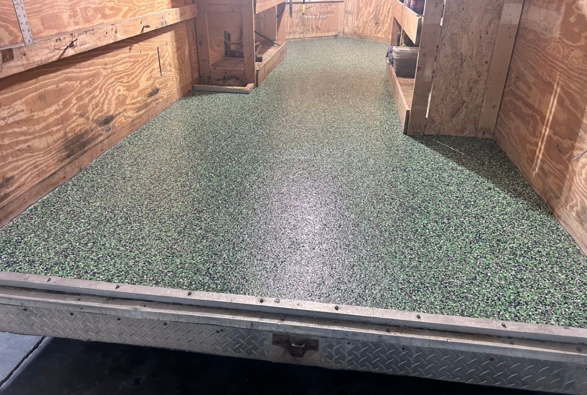 Green-speckled carpet in a wooden truck bed, viewed from the tailgate.
