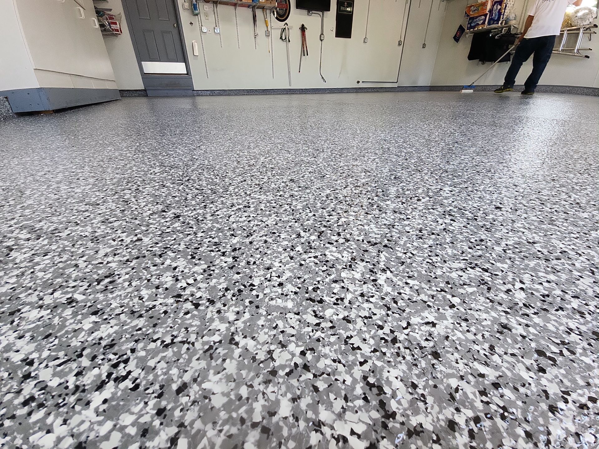 Speckled gray epoxy floor in a workshop or garage with a person standing in the background.