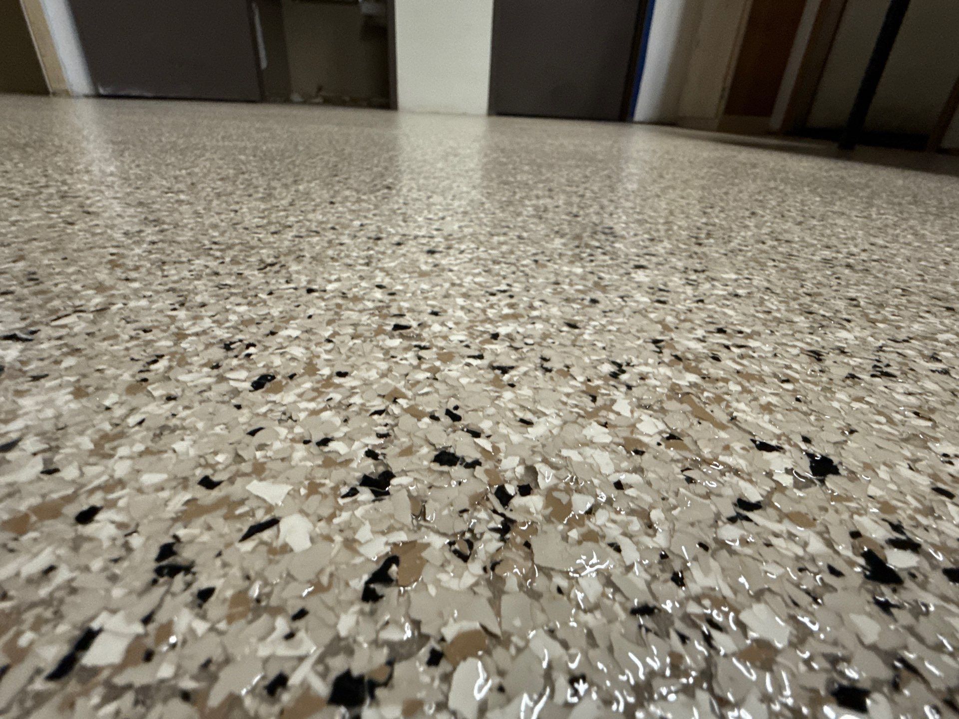Low-angle view of a speckled terrazzo floor in a hallway with doors in the background