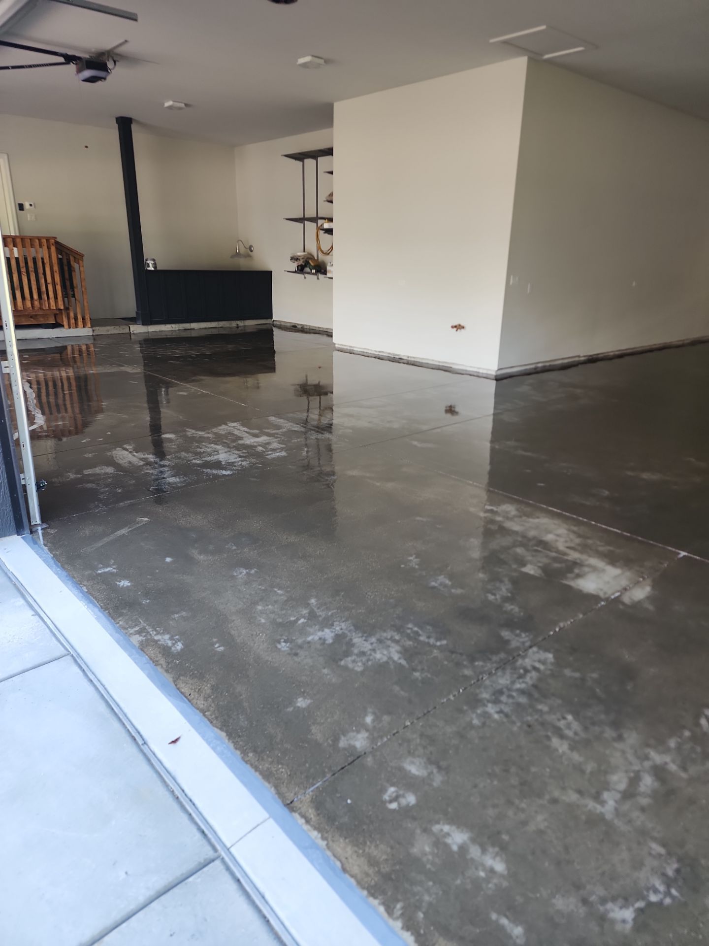 Flooded garage interior with a wet concrete floor and partially open doorway.