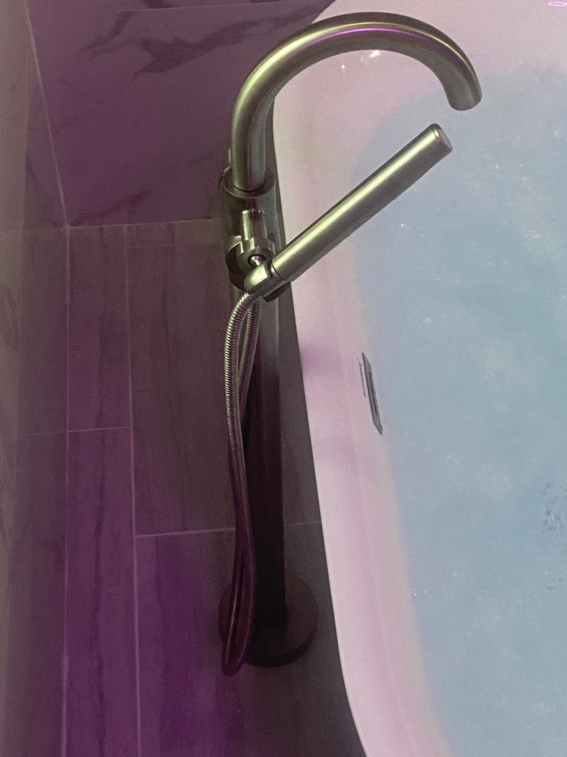 A faucet in a bathtub with purple and blue water