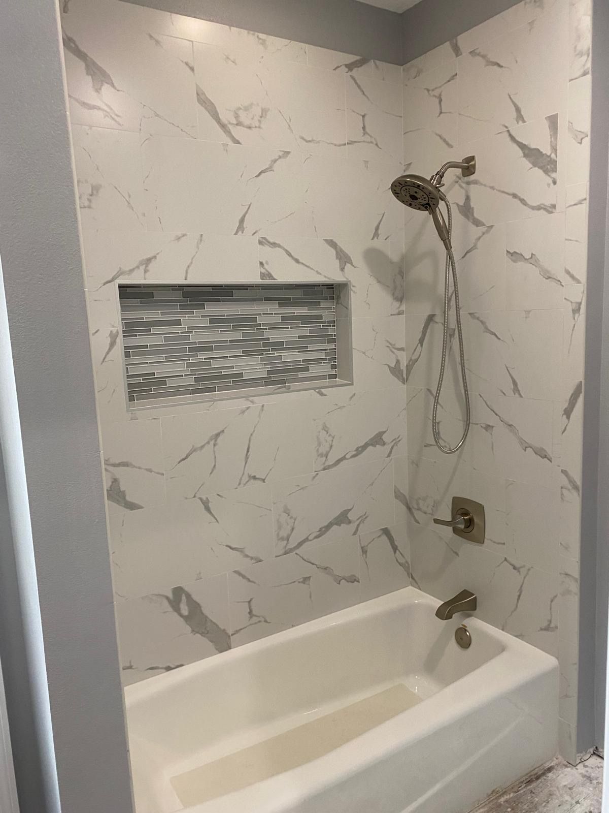 There is a bathtub in the shower with a shower head