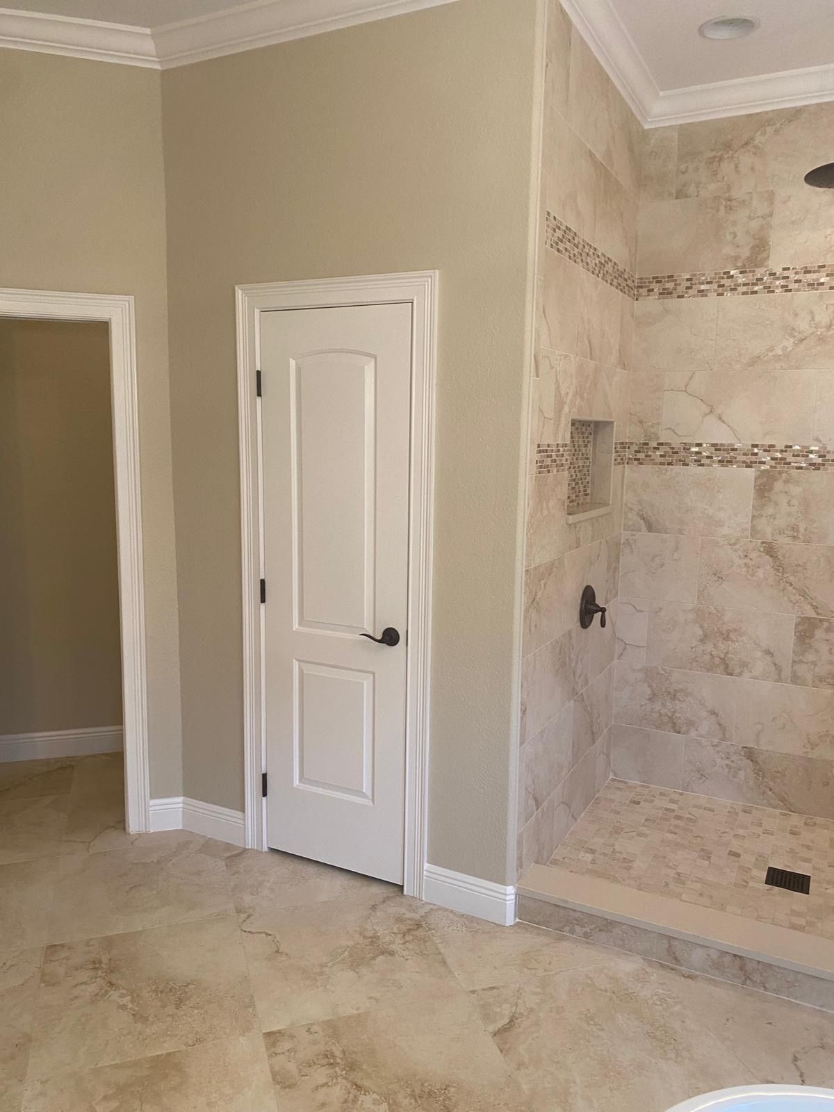 A bathroom with a walk in shower and a white door