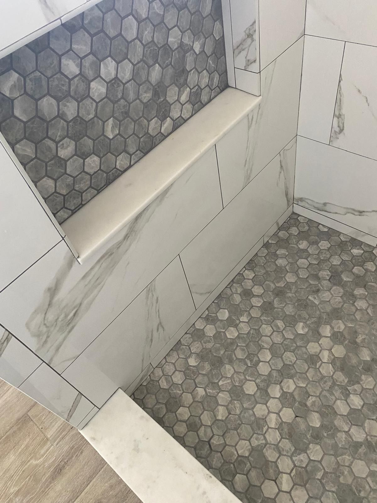 A shower with a shelf in the wall and a tiled floor