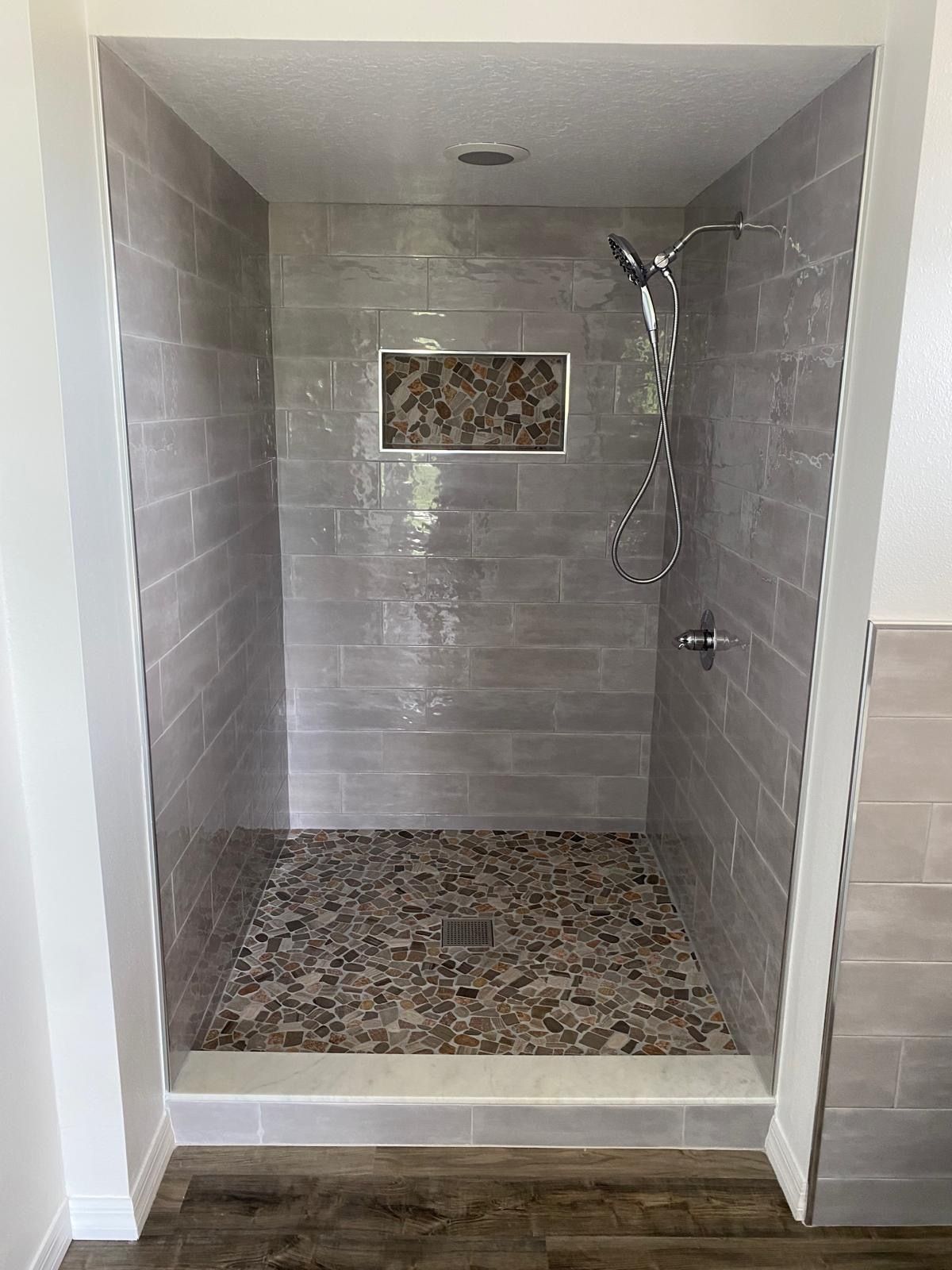 A walk in shower with a tiled floor and a shower head