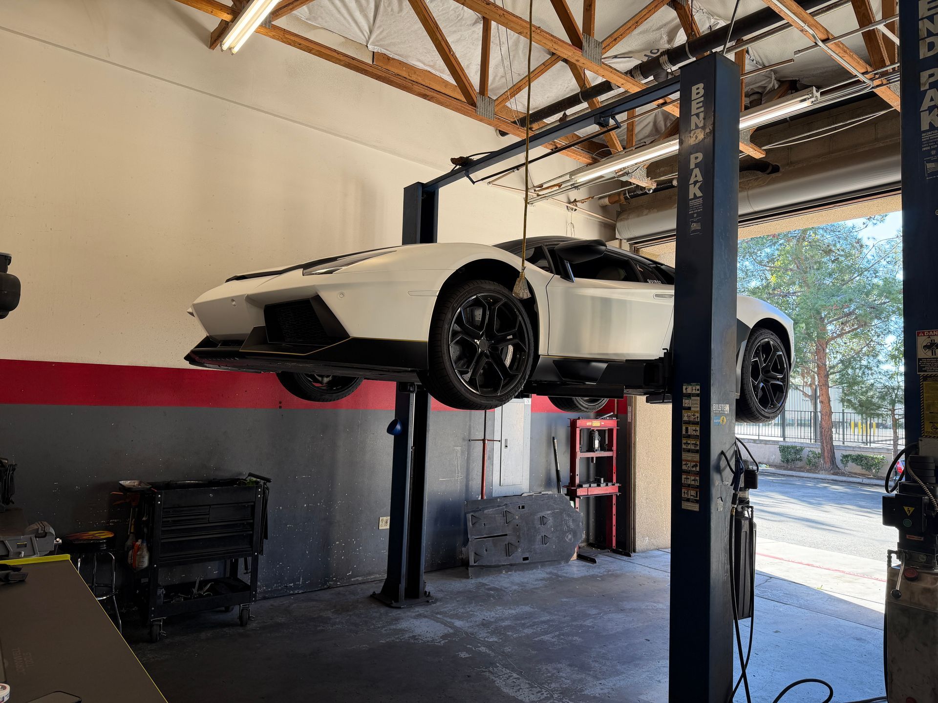 White Lamborghini raised on a car lift inside a garage.