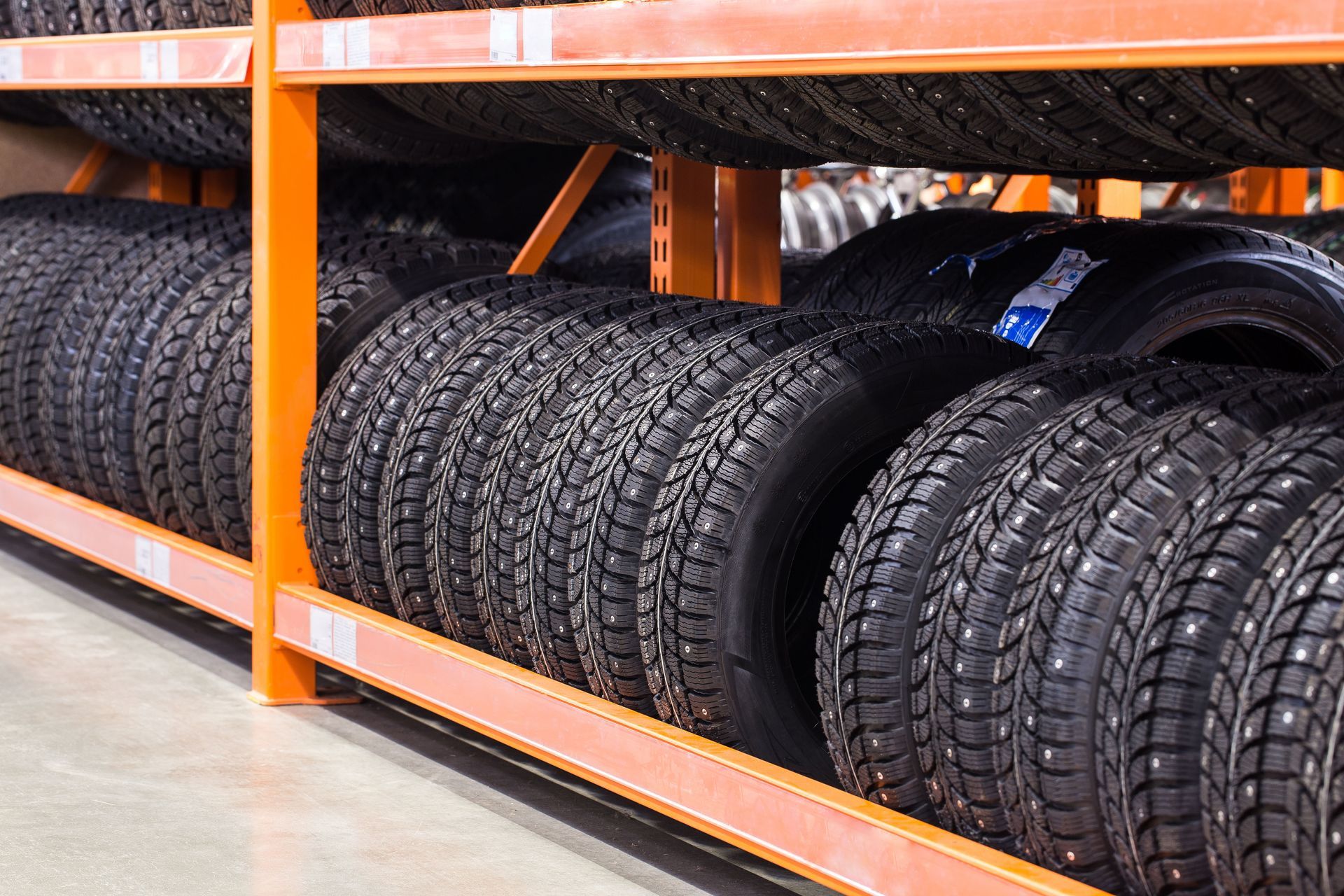 Tires stacked on orange metal shelves in a warehouse.
