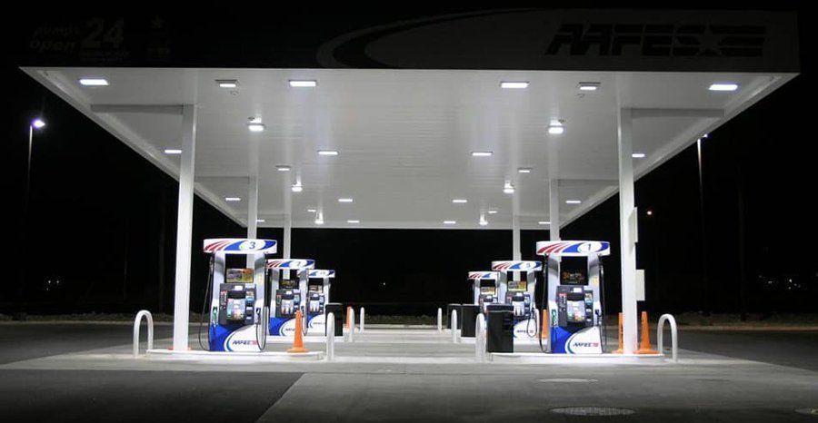 Empty gas station at night with bright white canopy lights and fuel pumps