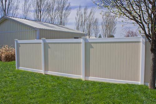 Three-panel white vinyl privacy fence in a grassy backyard beside a house.