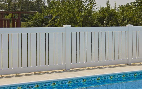 White backyard fence beside a swimming pool with blue tile border