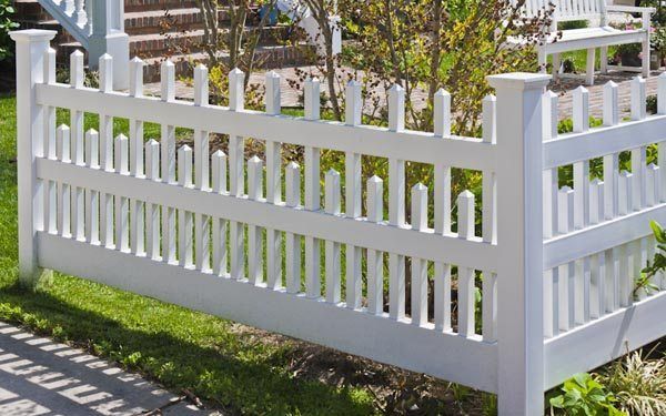 White picket fence around a garden beside a sidewalk