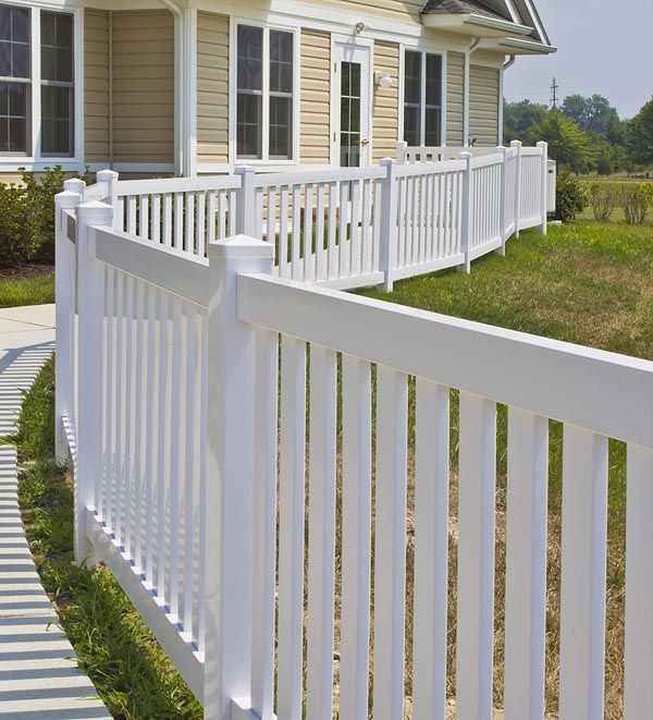 White vinyl fence lining a house’s front walkway and porch on a sunny day