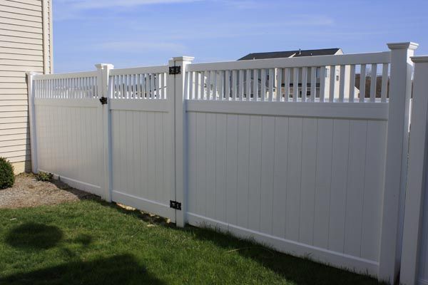 White vinyl privacy fence along a grassy yard under a clear sky