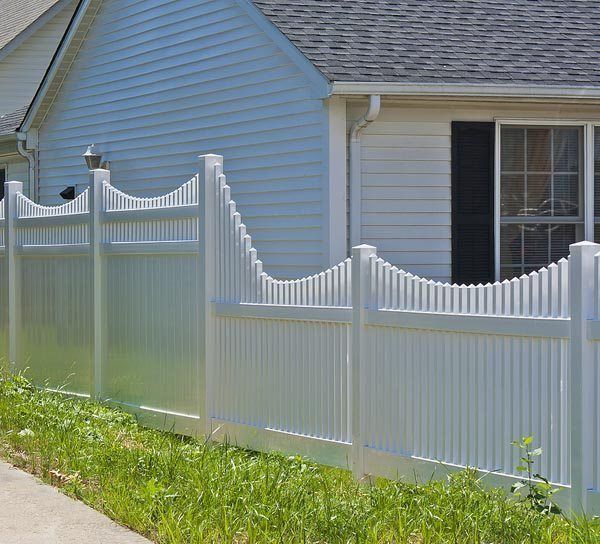 White vinyl fence beside a light blue house along a grassy sidewalk