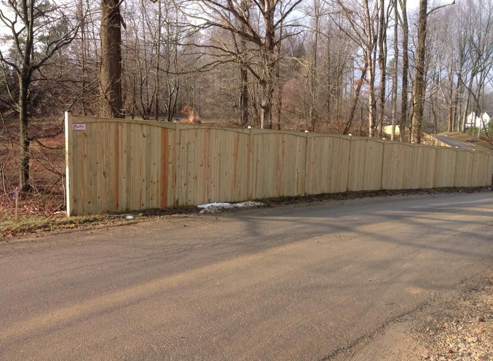 Long wooden fence along a quiet roadside in a leafless wooded area