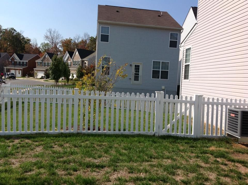 Suburban backyard with white picket fence and gray house on a sunny day