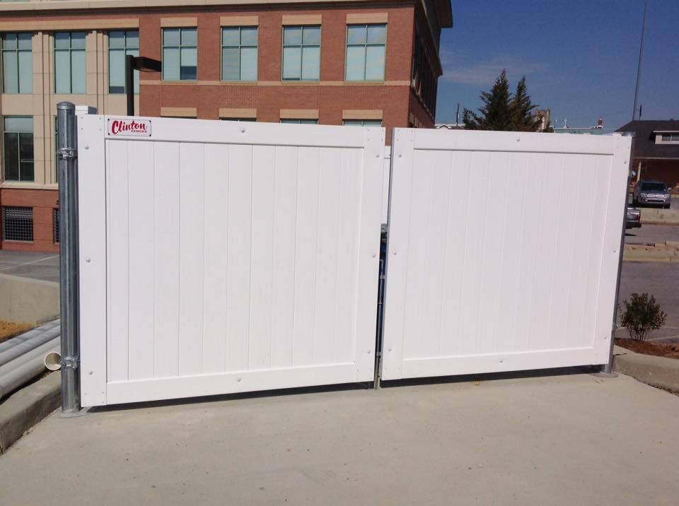 White foldable fence panels blocking a driveway in front of a brick building