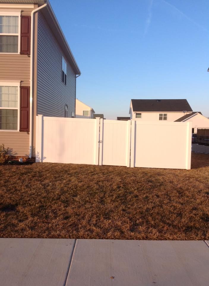 White privacy fence between suburban houses under a clear blue sky