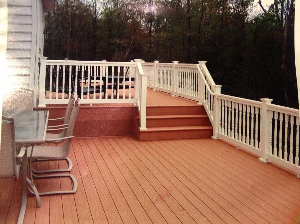 Wooden deck with steps, white railings, and a chair beside the house