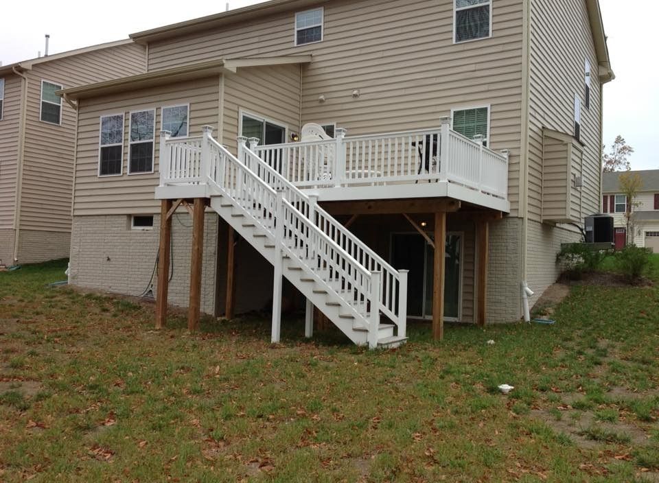 Backyard wooden deck with stairs attached to a beige two-story house