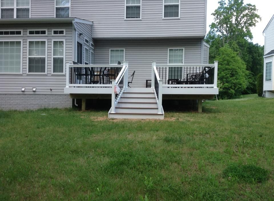 Backyard view of a gray house with twin decks, central stairs, and a grassy lawn