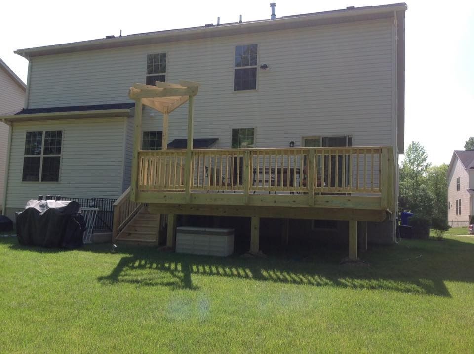 Backyard deck attached to a beige two-story house, with stairs and a grassy yard.