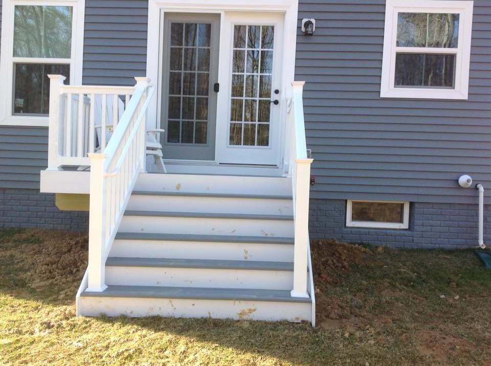 Blue house entry with white stairs, railings, and double front doors