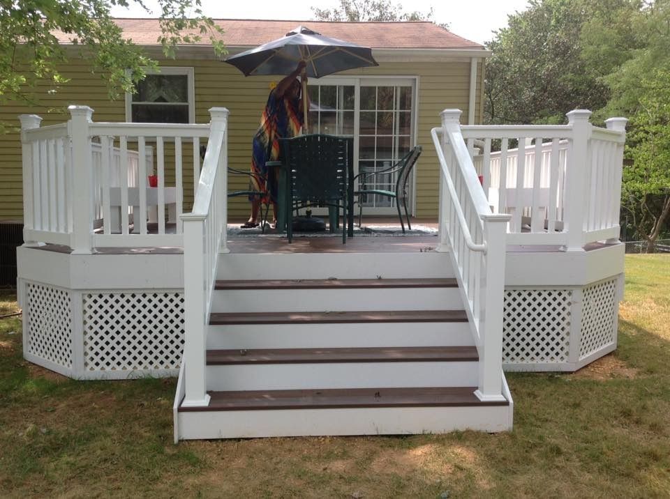 White backyard deck with steps, railings, and patio furniture in front of a house