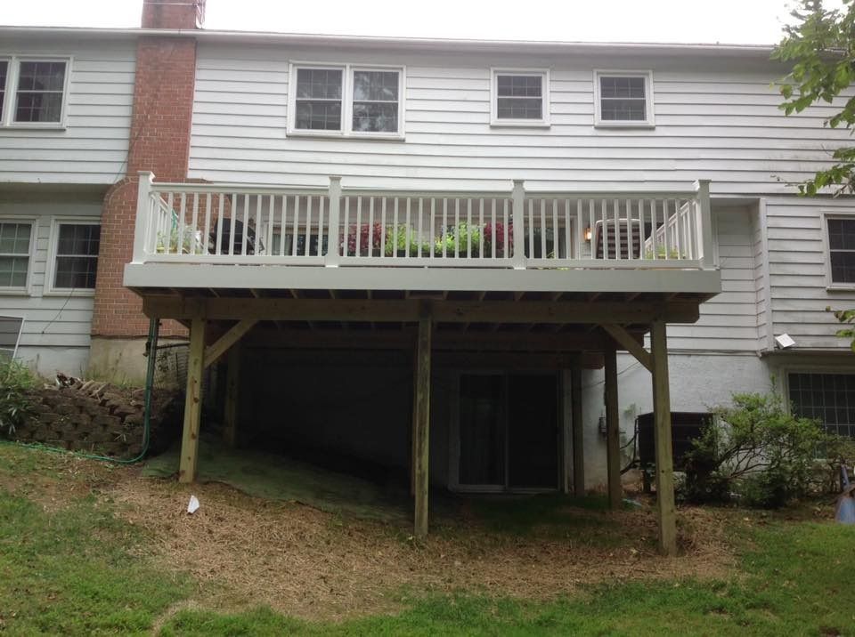 Back deck on a gray house with stairs down to a shaded patio below