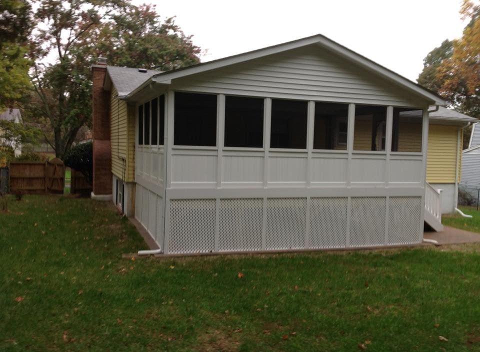 Small gray house with screened porch and white lattice skirt, surrounded by a grassy yard.