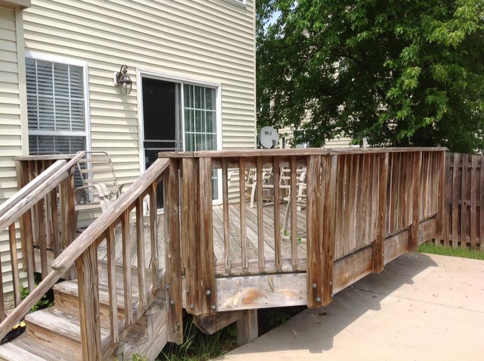 Wooden ramp with railings beside a house, showing weathered slats and a concrete walkway