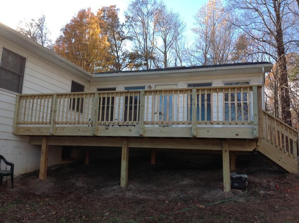 Wooden backyard deck with stairs attached to a house, surrounded by autumn trees