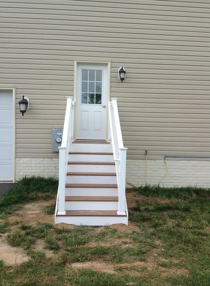 Exterior stairs leading to a white door on a beige-sided building
