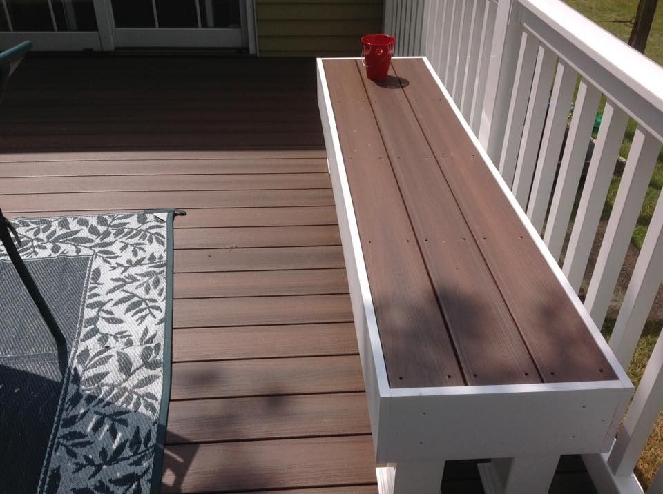Wooden porch bench with a red mug on top beside a patio chair and railing