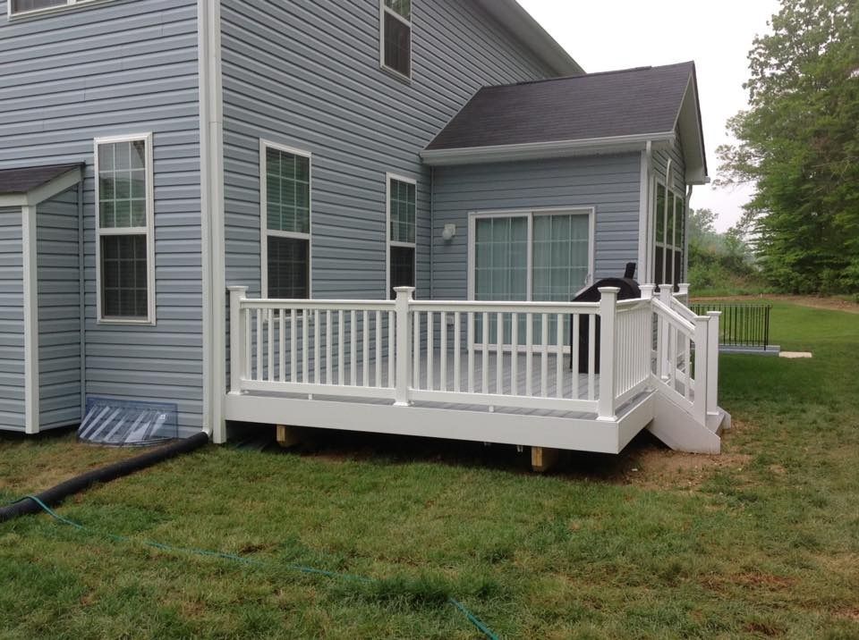 Gray house exterior with a white wheelchair-accessible ramp and small porch deck