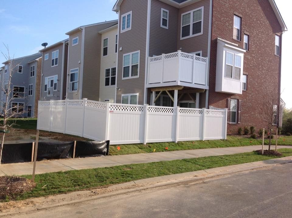 Row of townhouses with white fences and a sidewalk along a residential street