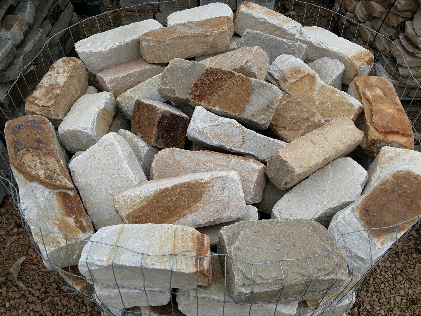 A pile of rocks in a wire basket on top of gravel.