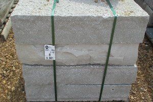 A stack of concrete blocks tied together with a green strap.