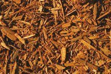 A pile of brown wood chips is sitting on the ground.