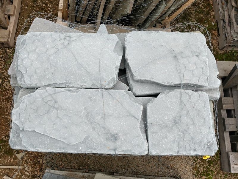 A pile of white marble slabs sitting on top of a wooden pallet.