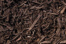 A pile of brown mulch is sitting on top of a pile of dirt.
