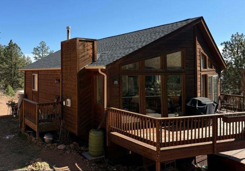 Wooden cabin with a covered porch and deck in a pine forest