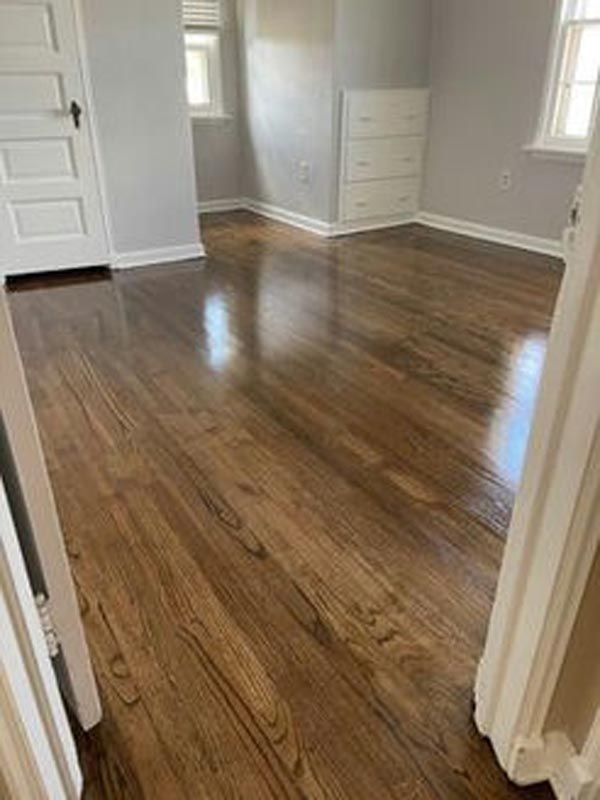 A bedroom with hardwood floors and a window.