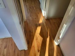 A hallway with hardwood floors and a shadow of a person on the floor.